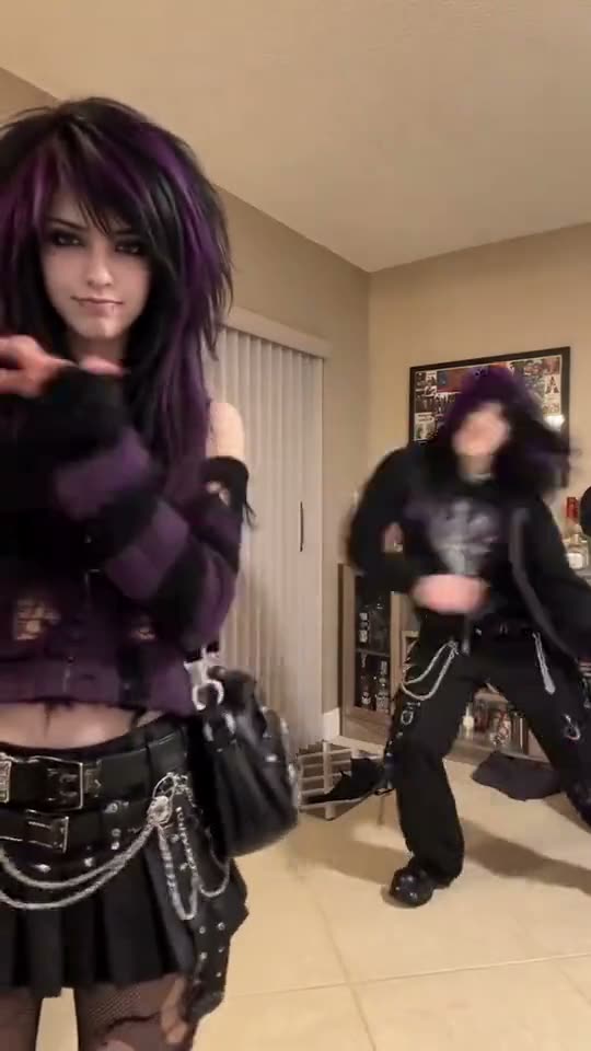 Hop hop hop dance: an emo duo with purple hair squish each other in a living room