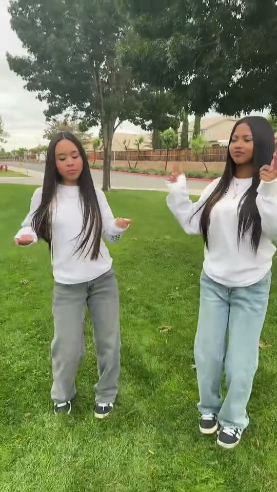 Puerto Rican mami dance: two friends with long dark hair in white tops do the dance on a lawn