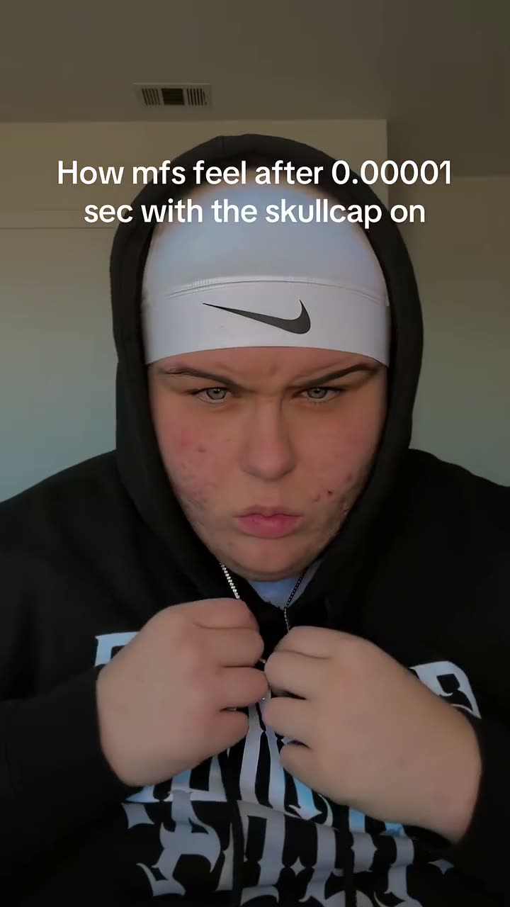 Skull cap trend: a guy with messy hair pulls on a white skull cap and turns serious with a black hoodie up